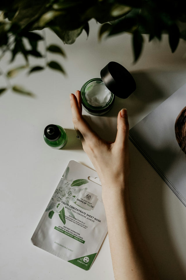Hand bij een potje crème en een serumflesje